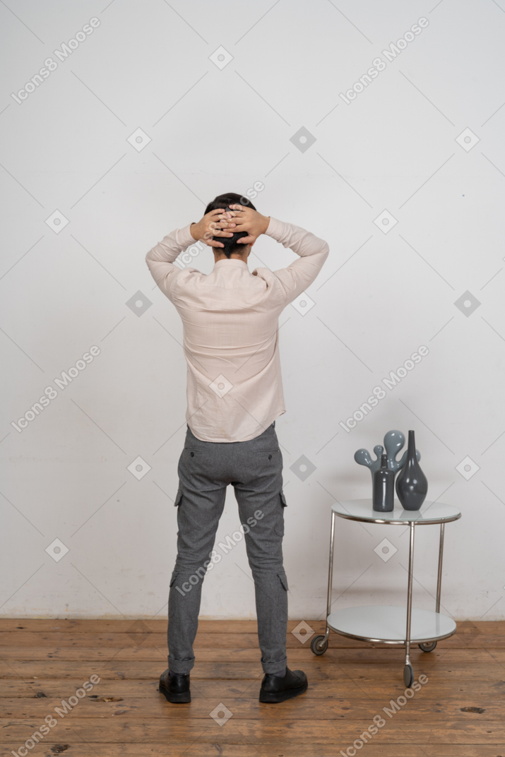 一个穿着休闲服的男人双手放在脑后站立的后视图