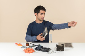 Un jeune homme en vêtements bleus occasionnels travaillant avec les détails de l'ordinateur