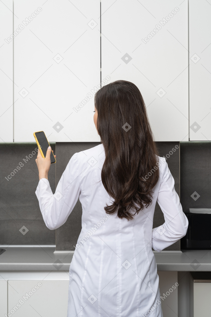 Back view of a female doctor using her phone