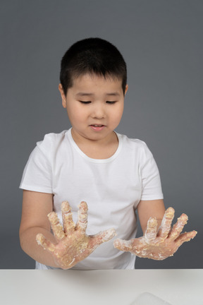 一个惊讶的小男孩，看着他面粉的手