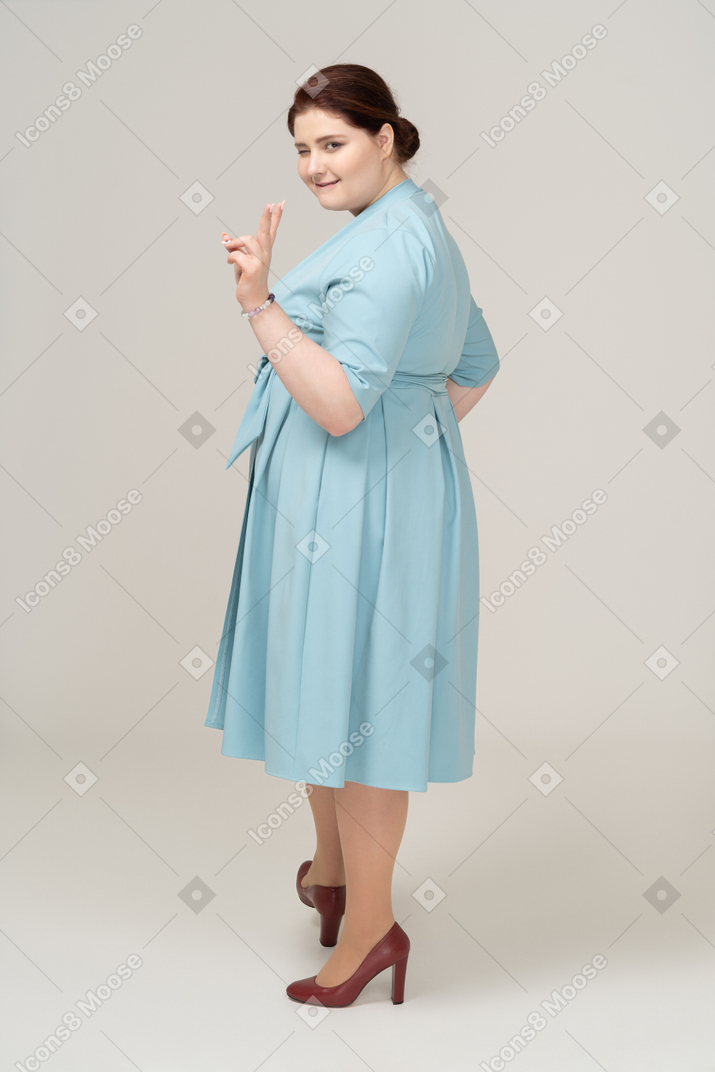 Side view of a woman in blue dress showing v sign
