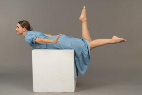 Vue latérale d'une jeune femme allongée sur un cube