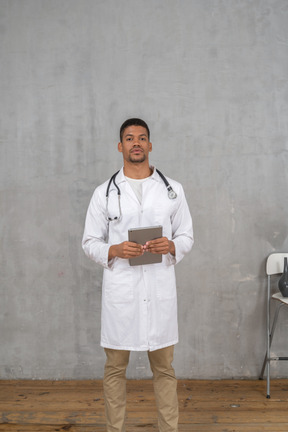 Front view of a male doctor holding a tablet