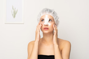 Portrait of young woman with nose bandage touching her face