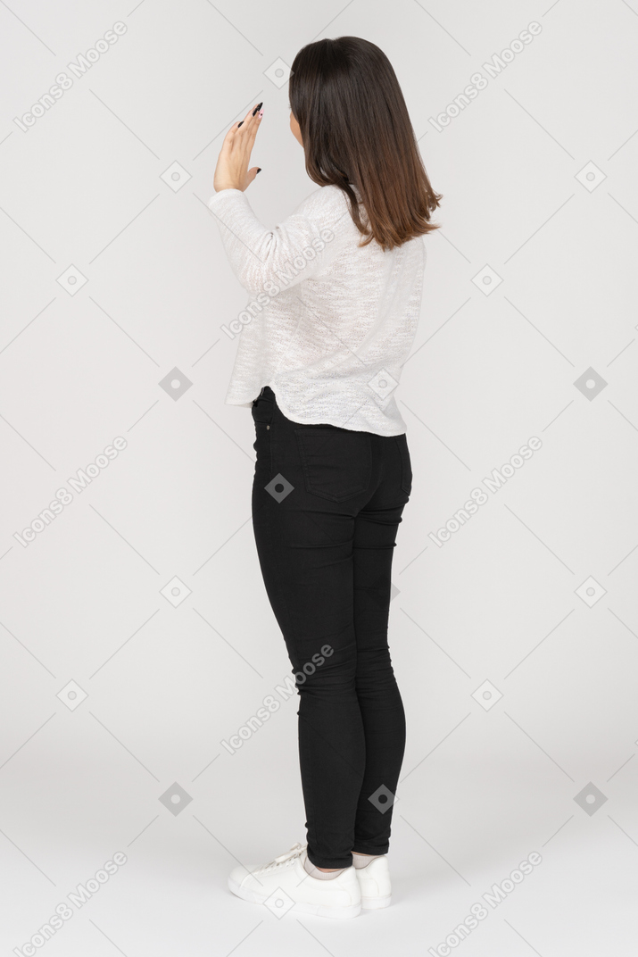 Vista posteriore di tre quarti di una giovane donna indiana che saluta in abbigliamento casual