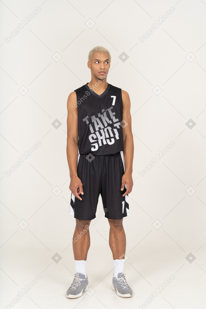 Vista frontale di un giovane giocatore di basket maschio confuso che guarda da parte