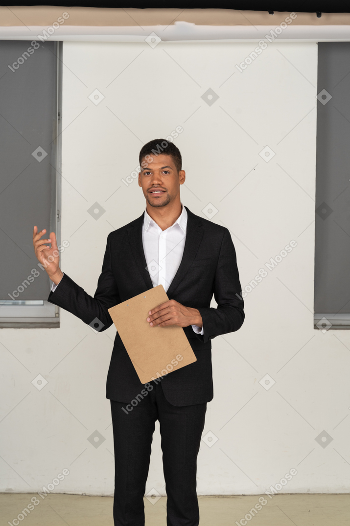 Jeune employé de bureau en costume noir prononçant un discours