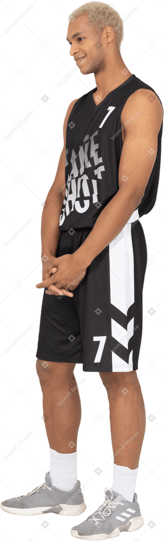 Three-quarter view of a shy young male basketball player holding hands together