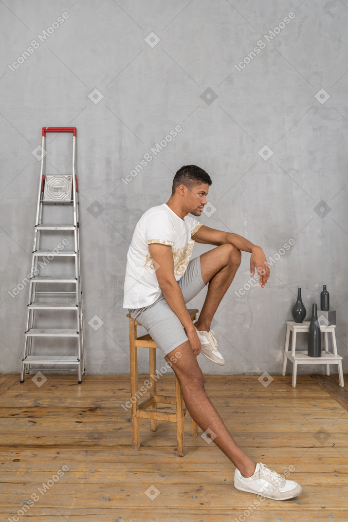 Side view of man sitting on stool