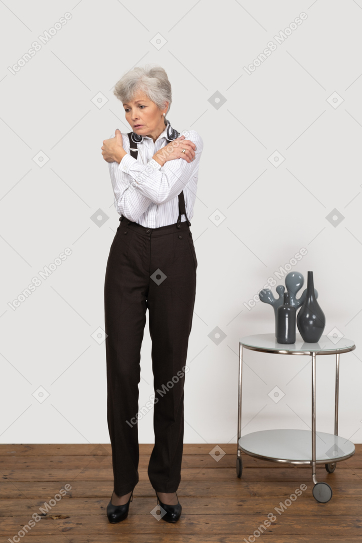Front view of an old lady in office clothing embracing herself