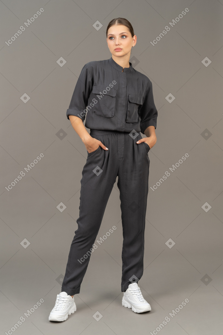 Front view of a young woman in a jumpsuit putting hands in pockets