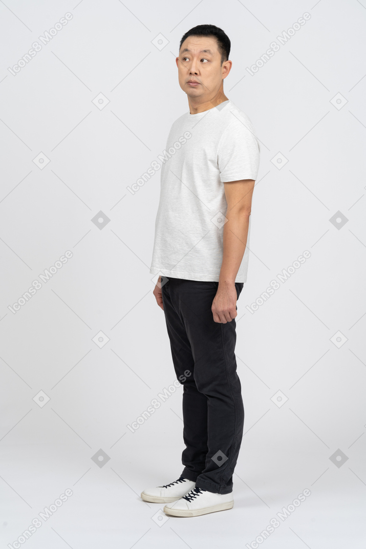 Man in casual clothes standing still and lookin at something with interest