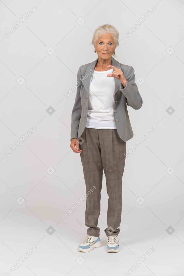Vue de face d'une vieille dame en costume montrant une petite taille de quelque chose