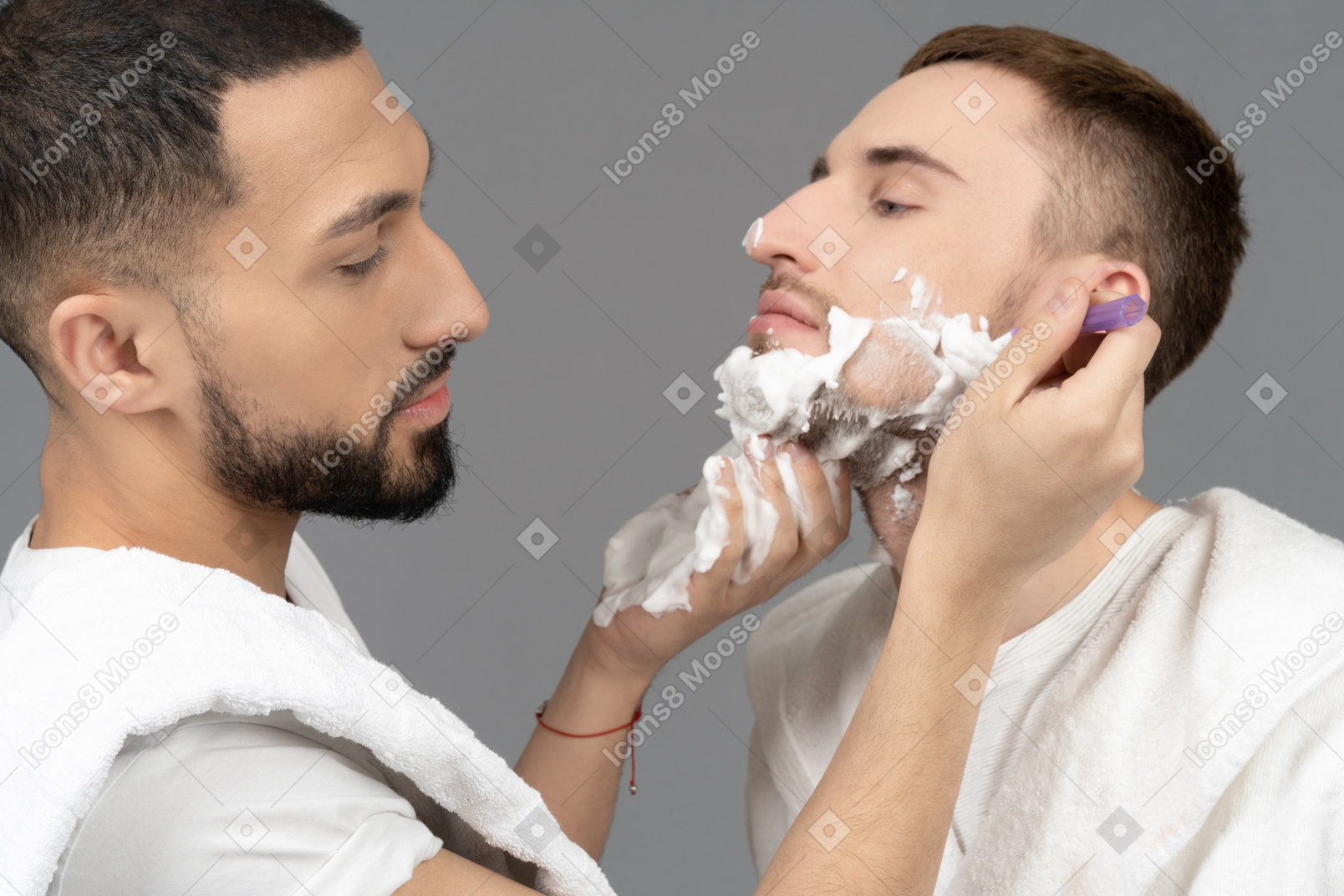 Close-up of a man shaving partner's face
