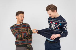 Brothers trying on knitted christmas sweaters