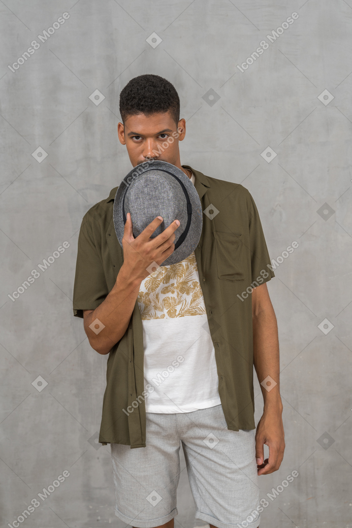 Young man in casual clothes holding hat