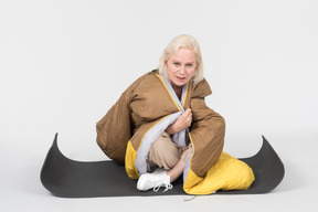 Mature woman sitting on tourist mat wrapped in blanket