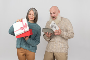 Elegante pareja de ancianos dando regalos el uno al otro