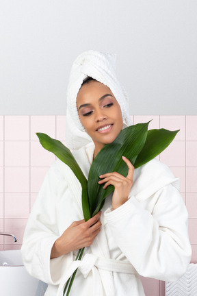 A woman in a bathrobe holding a plant