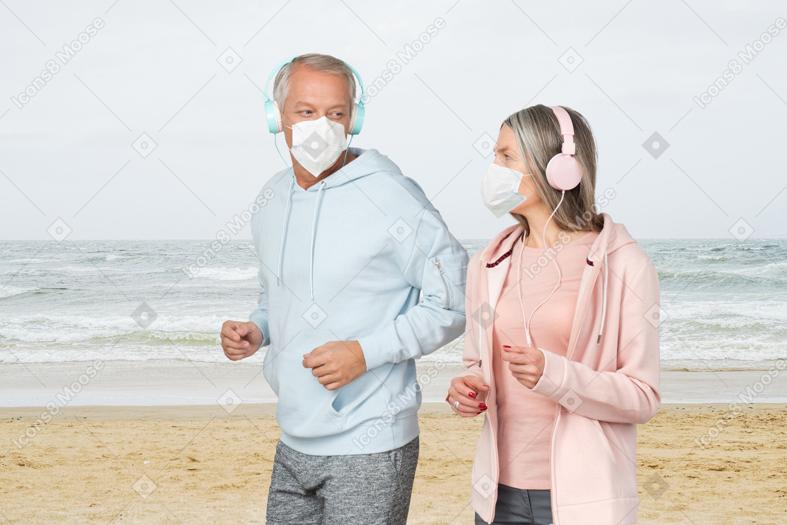 Old man and old woman running on a beach with face masks on
