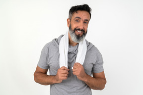 Smiling mature man holding towel on his neck with both hands