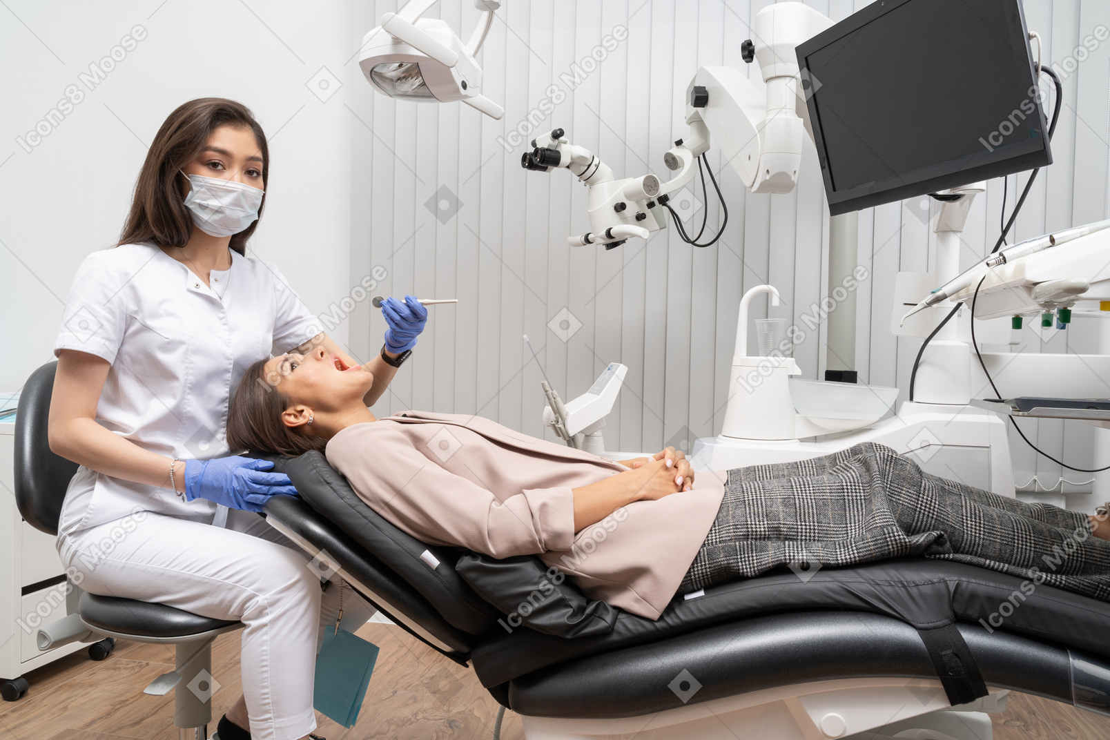 A figura intera di un dentista femminile che esamina la sua paziente di sesso femminile che giace in un armadietto dell'ospedale