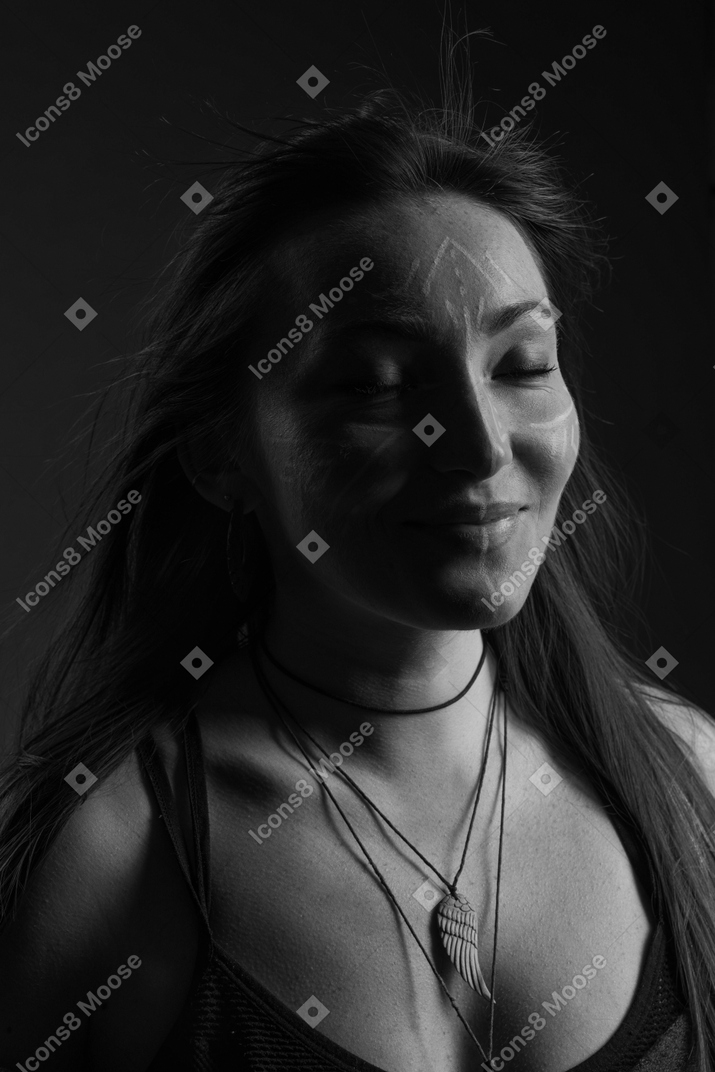 Head to shoulder noir portrait of a  smiling young female with face art and her eyes closed