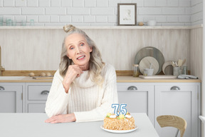 A woman sitting at a table with a cake in front of her