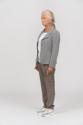 Anciana en chaqueta gris de pie en el perfil