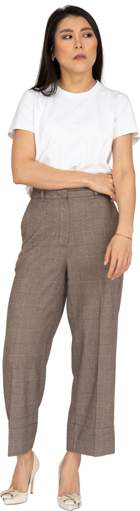 Vista frontale di una giovane donna scontenta in calzoni e maglietta