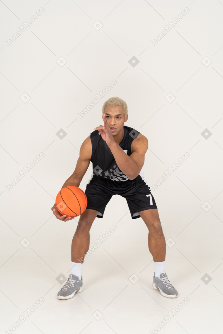 Vista frontal de um jovem jogador de basquete fazendo dribles