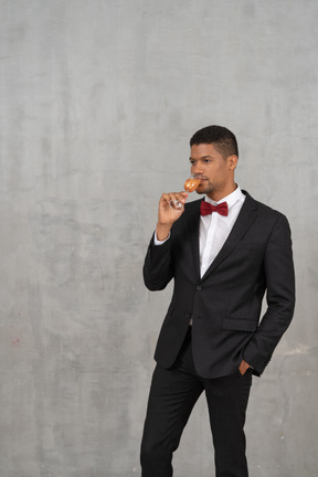 Мужчина в костюме и галстуке-бабочке пьет из бокала шампанского