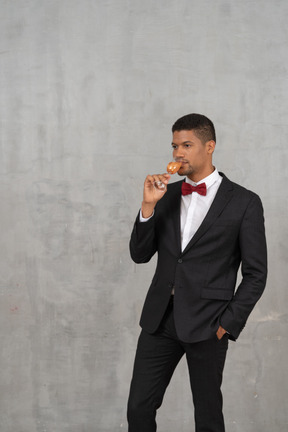 Homme en costume et noeud papillon buvant dans un verre de champagne