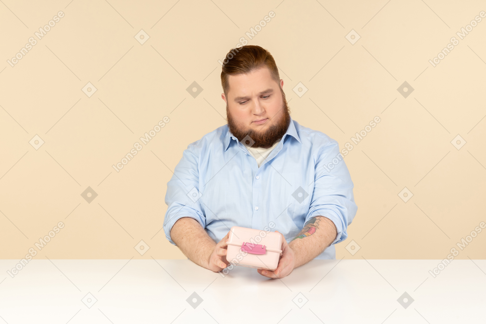 Большой человек сидит за столом и держит коробку для завтрака