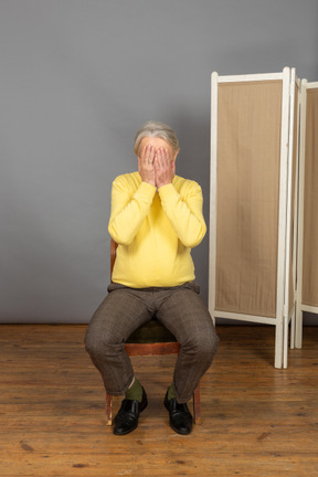 Middle-aged man covering his face with his hands