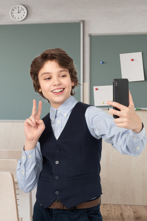 A schoolboy taking a selfie in a class
