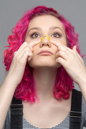 Teenage girl applying plaster on injured nose