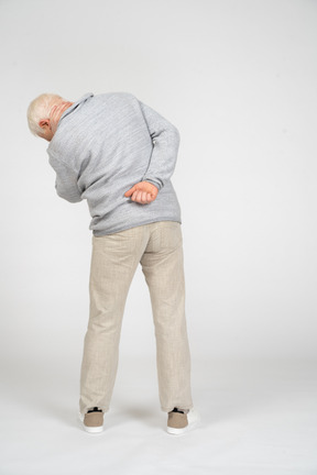 Back view of man with his hand on his lower back bending to the side