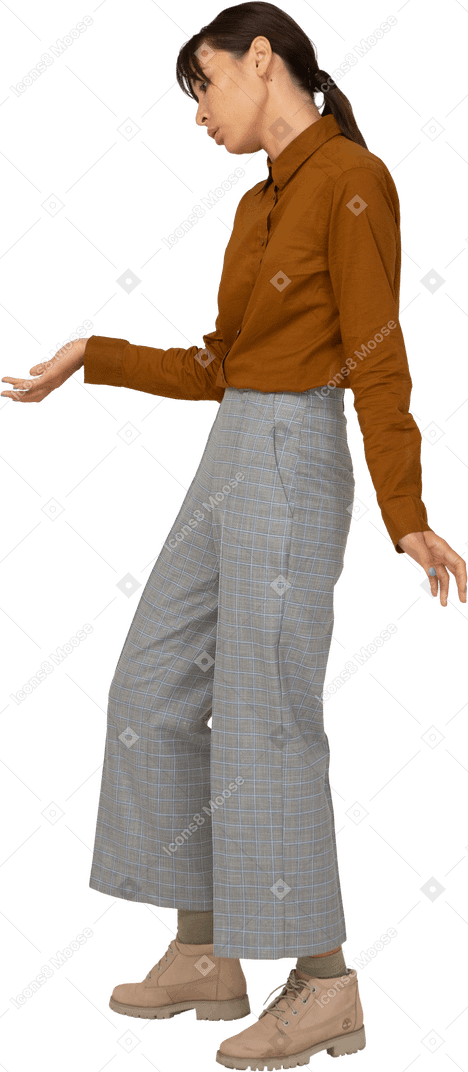 Vista di tre quarti di una giovane donna asiatica in calzoni e camicetta che fa una riverenza
