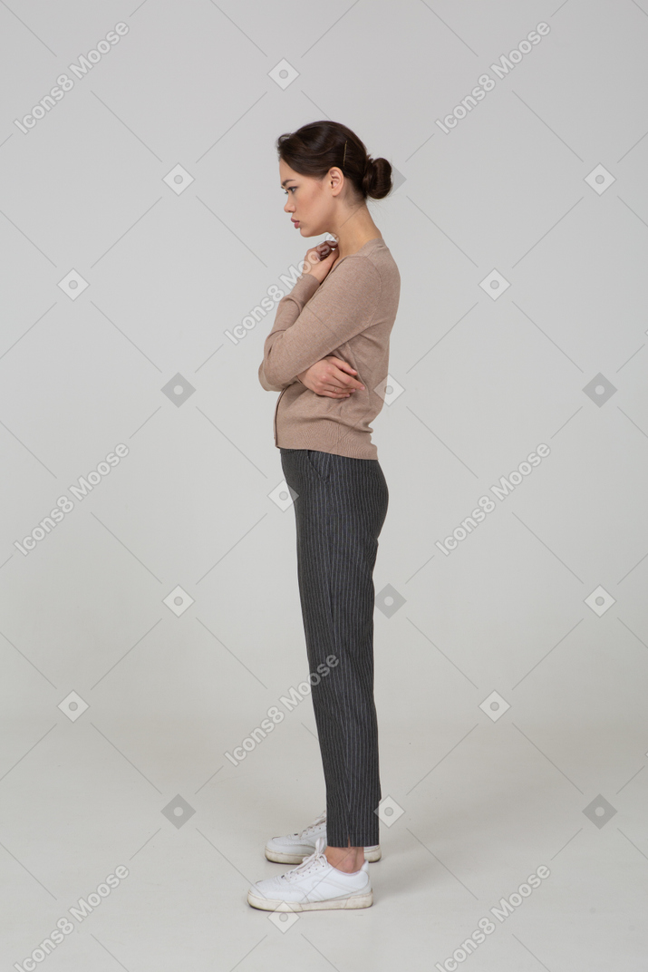 Side view of a thoughtful young lady in beige pullover crossing hands