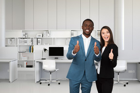 A man and woman giving thumbs up in an office
