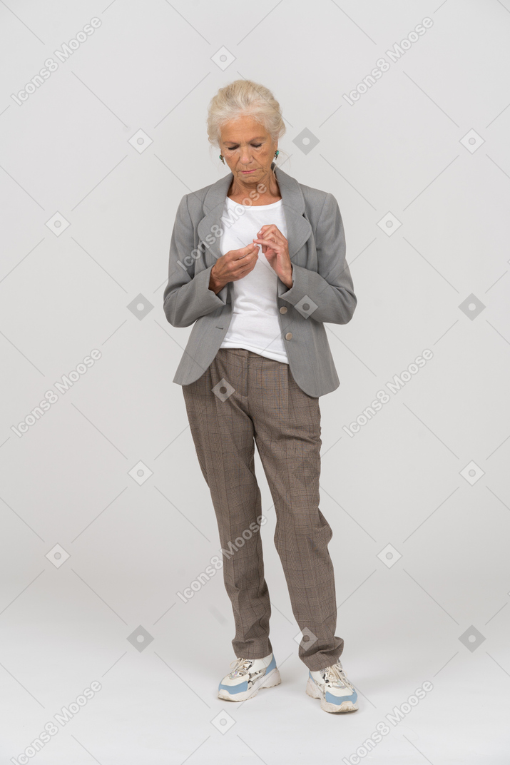 Front view of a thoughtful old lady in suit looking at her hands