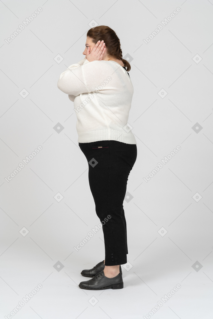 Side view of a plump woman in casual clothes closing ears