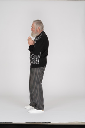 Side view of an old man standing with his hands folded