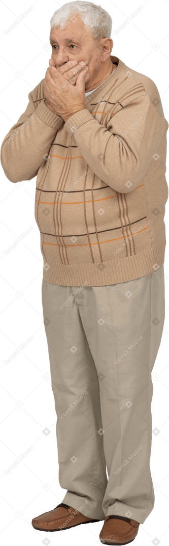 Vista frontal de un anciano asustado con ropa informal cubriendo la boca con las manos