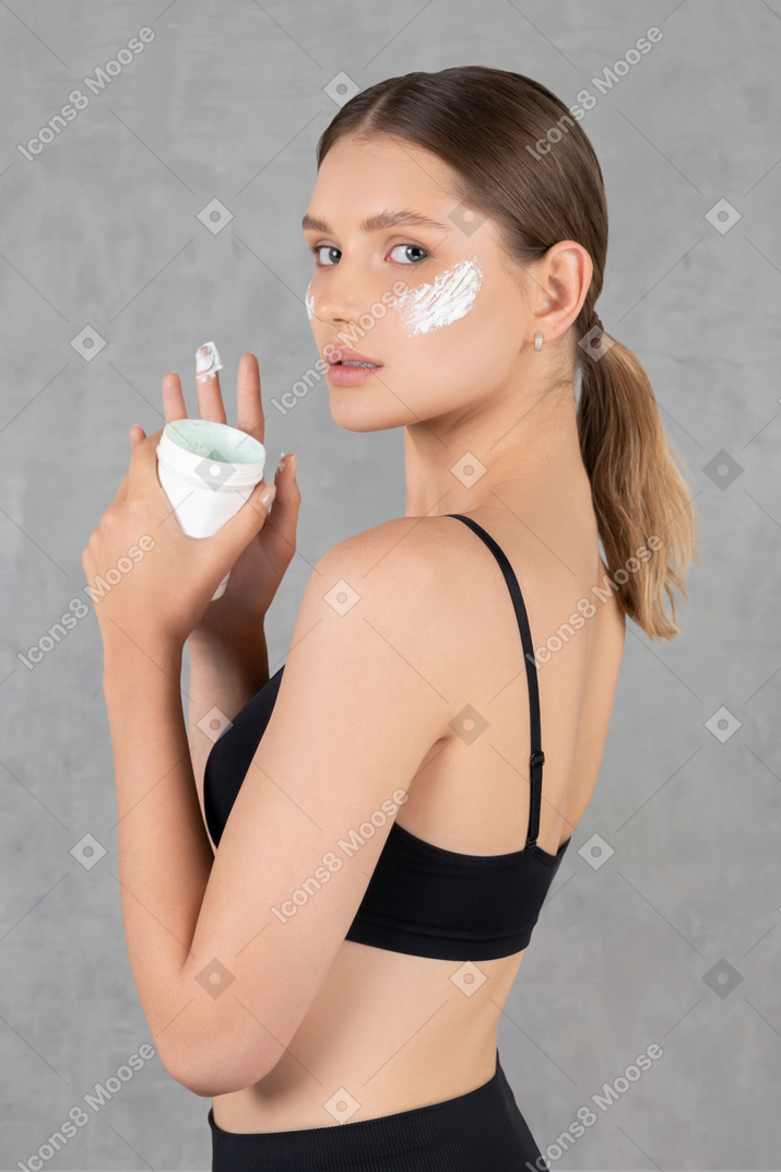 Portrait of a young woman with white cream applied on her skin