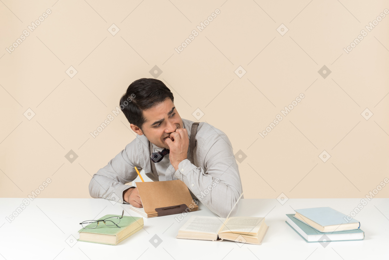 Laughing young caucasian student sitting at the table and writing something down in the notebook