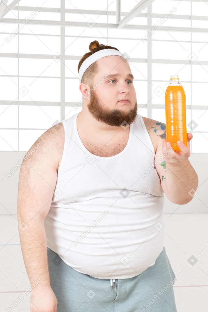 A fat man holding a bottle of orange juice