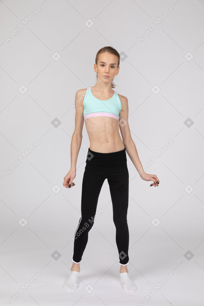Vista frontal de uma adolescente em roupas esportivas olhando para a câmera