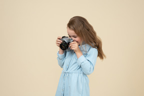 Bambina carina che tiene una macchina fotografica